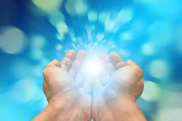 Hands palms up with blue sphere representing energy in the middle